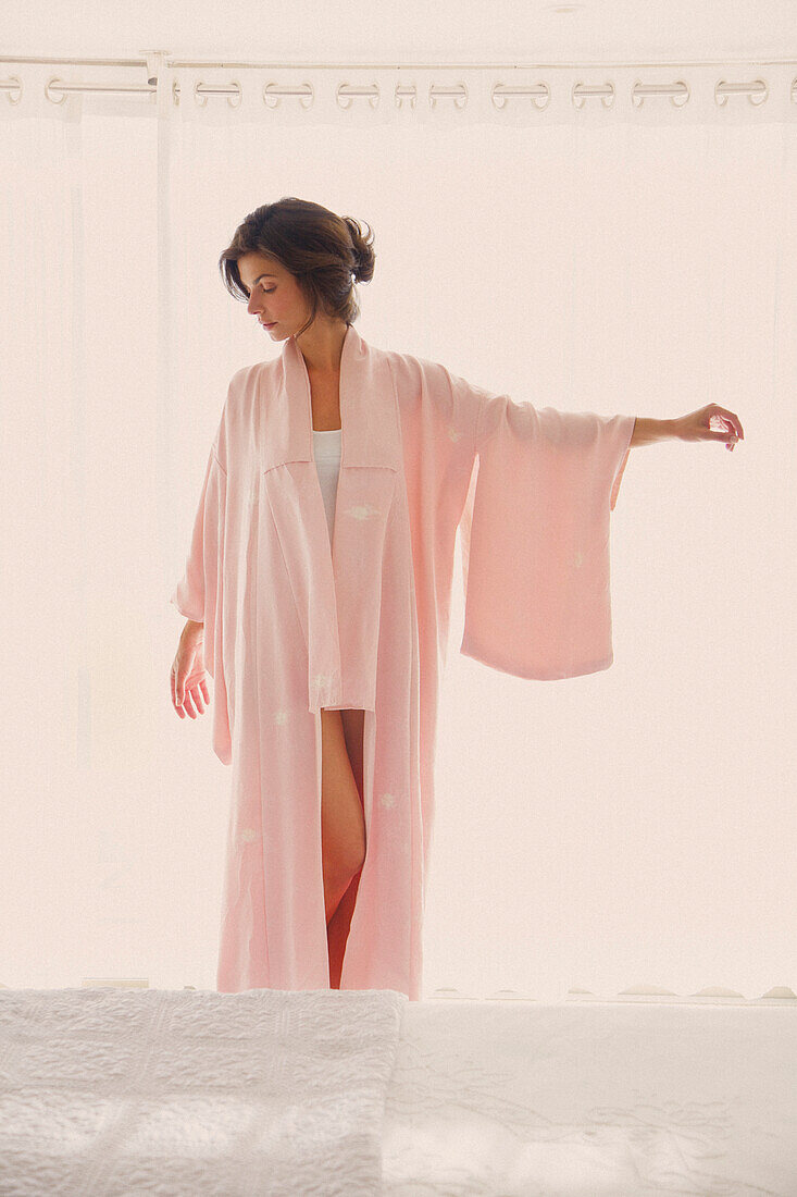 Frau in rosa Kimono stehend mit erhobener Hand