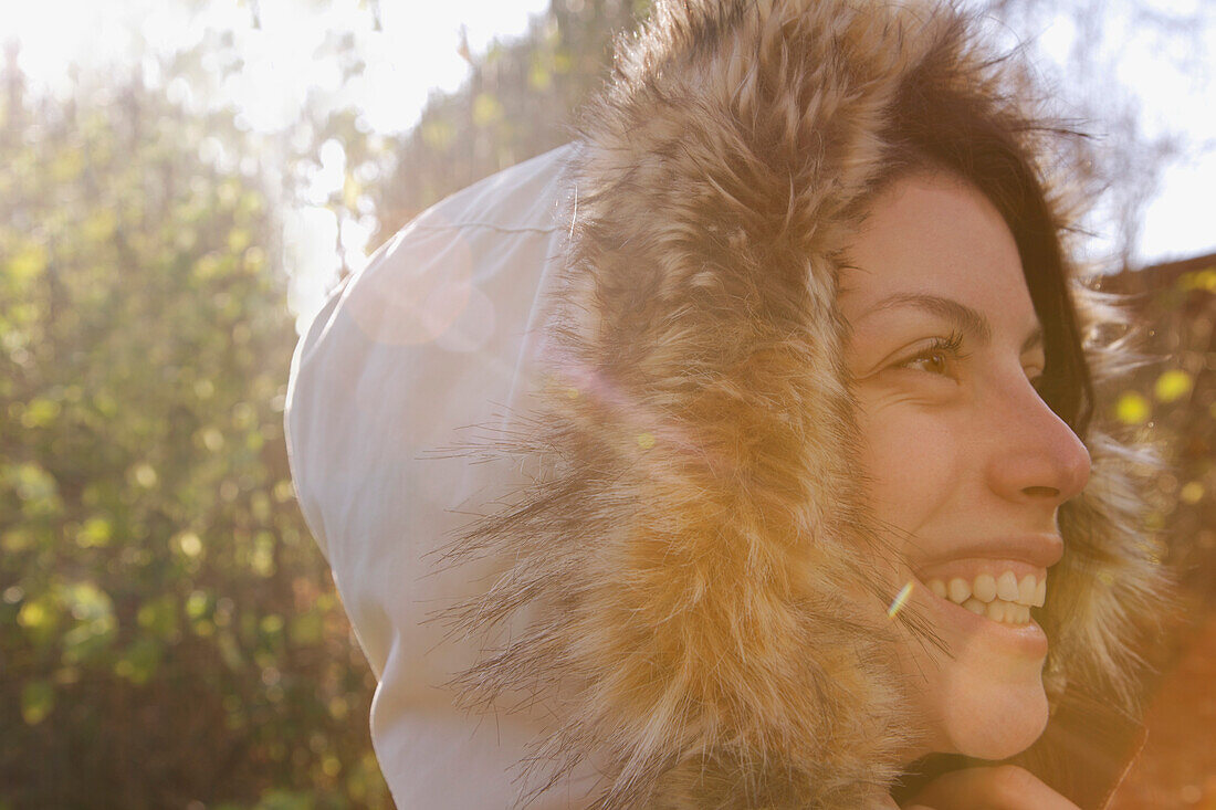 Close up profile of a smiling woman wearing a hooded parka