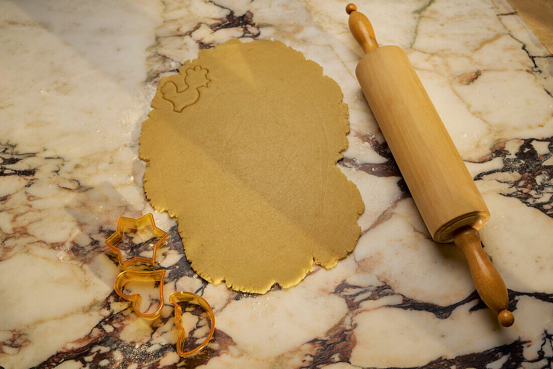Still life cookie dough and rolling pin on marble counter with cookie cutters
