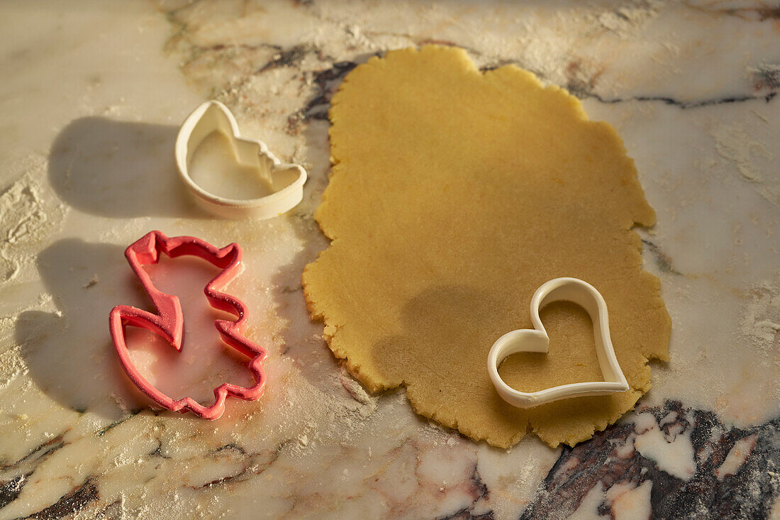 Cookie cutters and cookie dough on marble counter