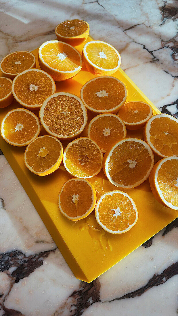 Frische Orangenquerschnitte auf Schneidebrett auf Marmortheke