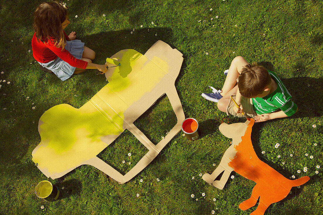 Kinder bemalen Pappausschnitte im Garten