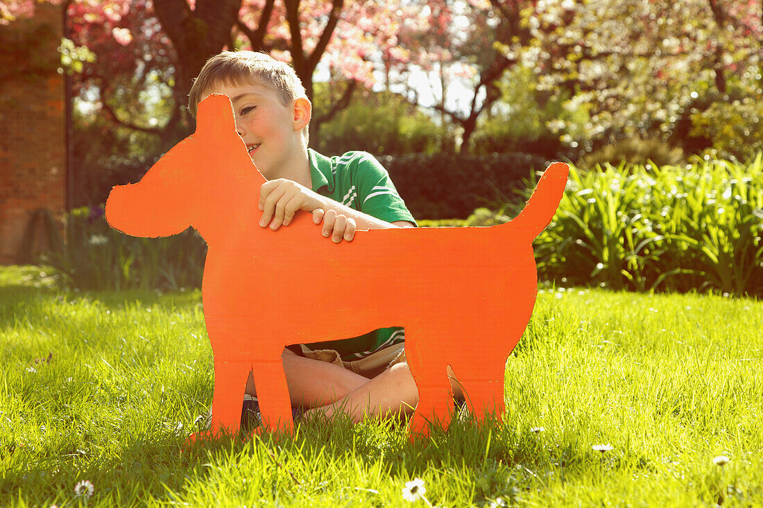 Young Boy Holding Cardboard Cut Out in Shape of Dog