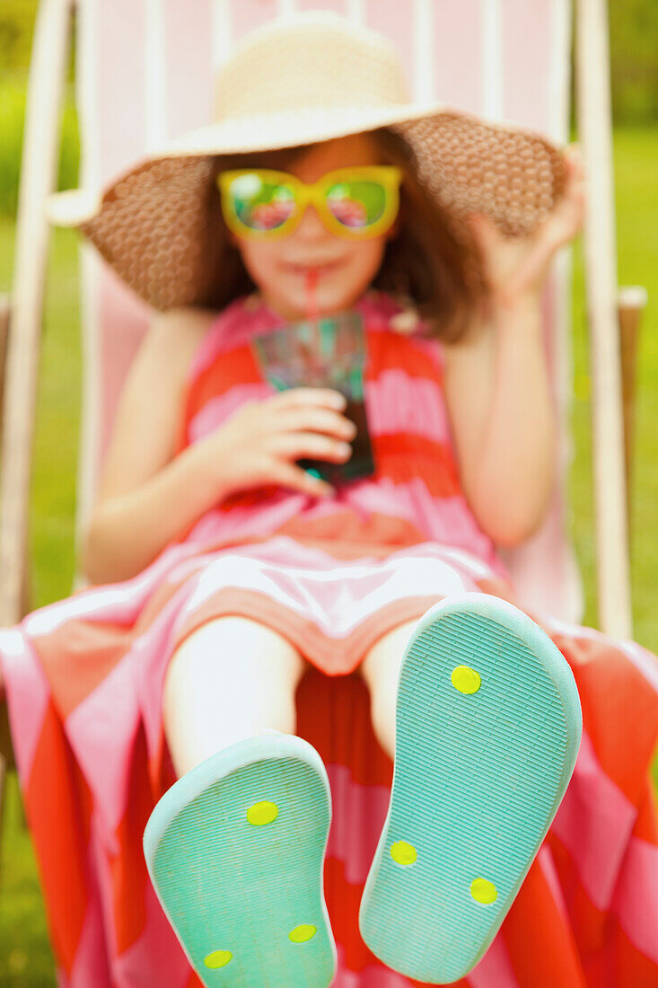 Mädchen auf Liegestuhl trägt Flip Flops