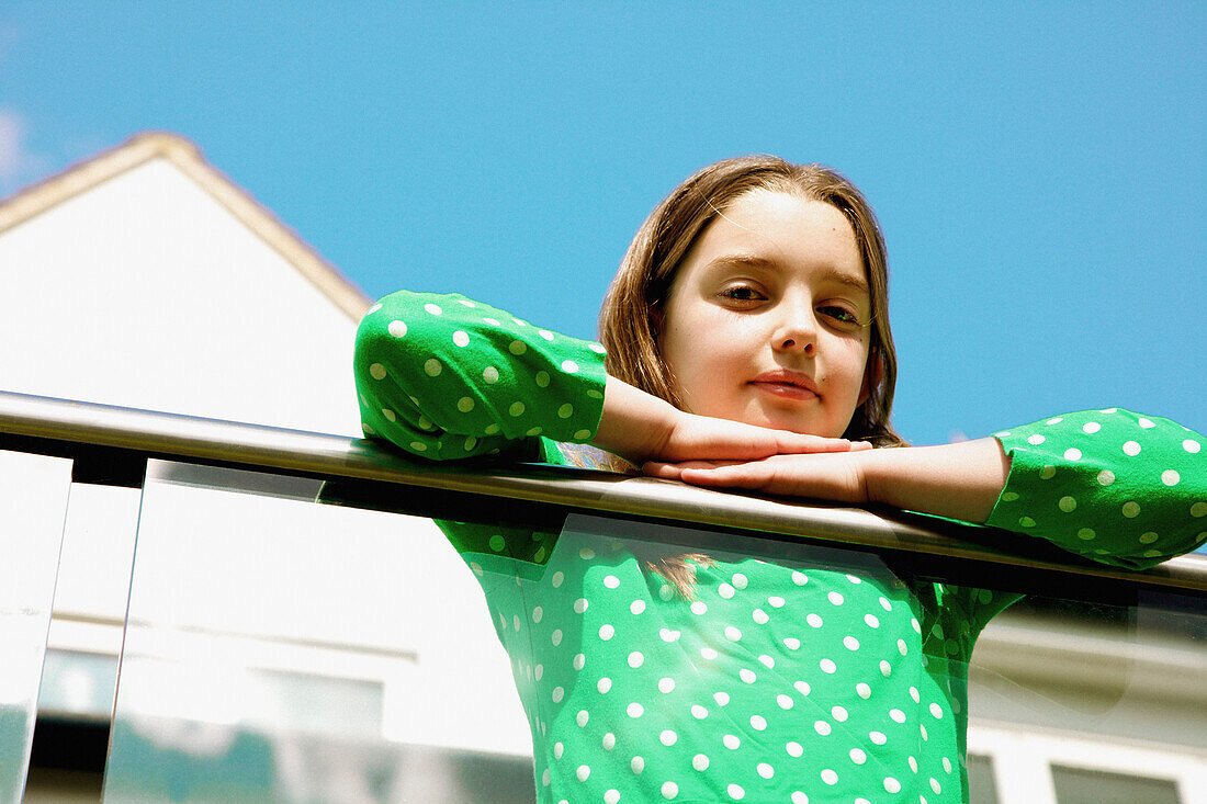 Young Girl Leaning on Balcony Railing