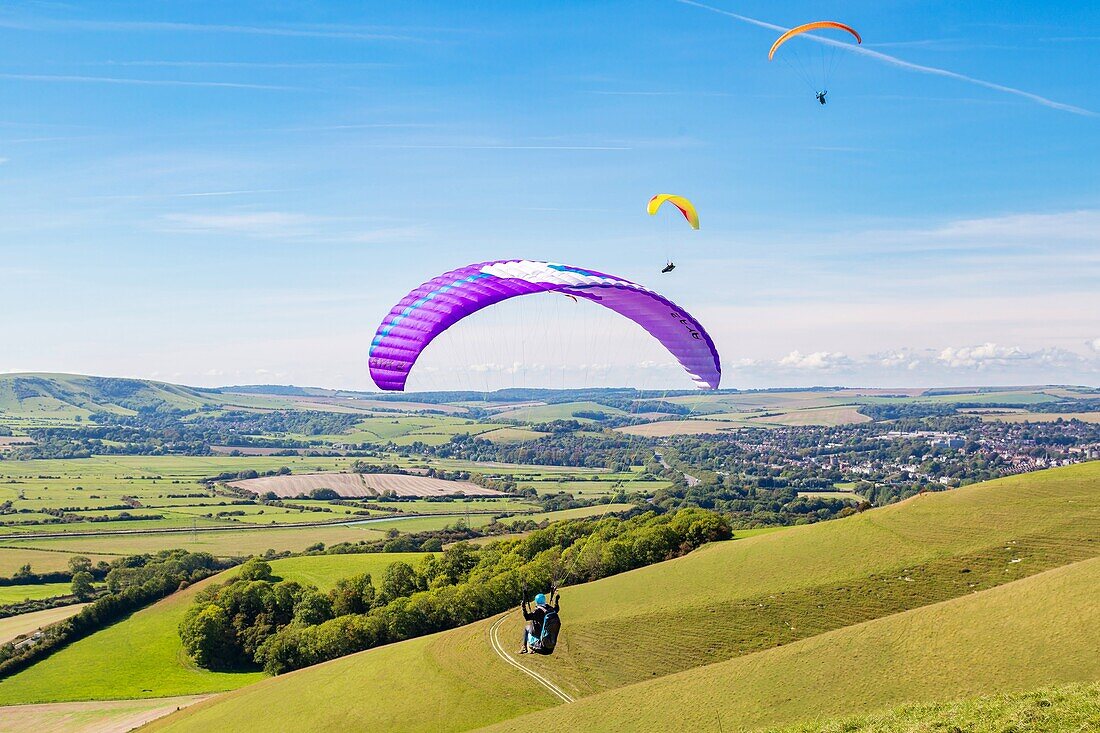 Gleitschirmflieger am Mount Caburn, die über der Grafschaftsstadt Lewes, East Sussex, England, Vereinigtes Königreich, Europa fliegen