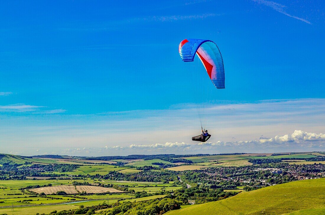 Gleitschirmflieger am Mount Caburn, die über der Grafschaftsstadt Lewes, East Sussex, England, Vereinigtes Königreich, Europa fliegen