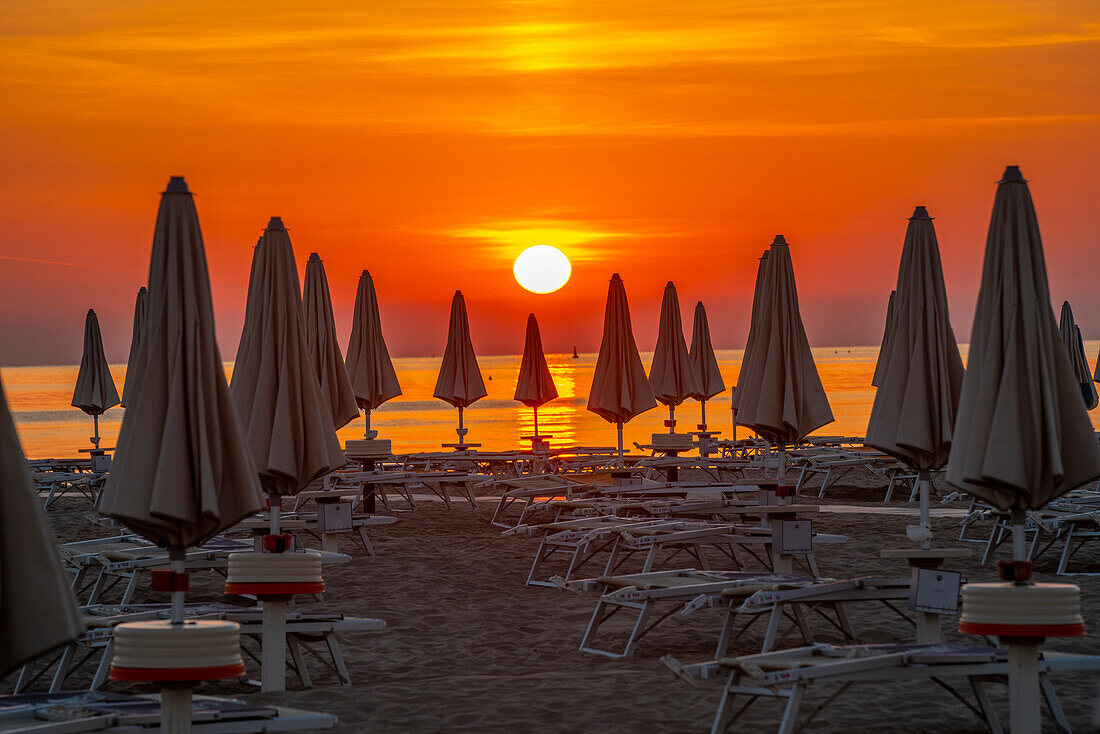 View of sunrise and sunshades on the Lido on Rimini Beach, Rimini, Emilia-Romagna, Italy, Europe