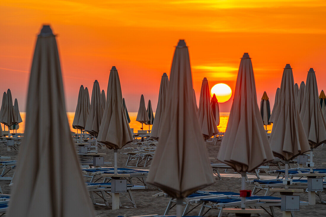 View of sunrise and sunshades on the Lido on Rimini Beach, Rimini, Emilia-Romagna, Italy, Europe