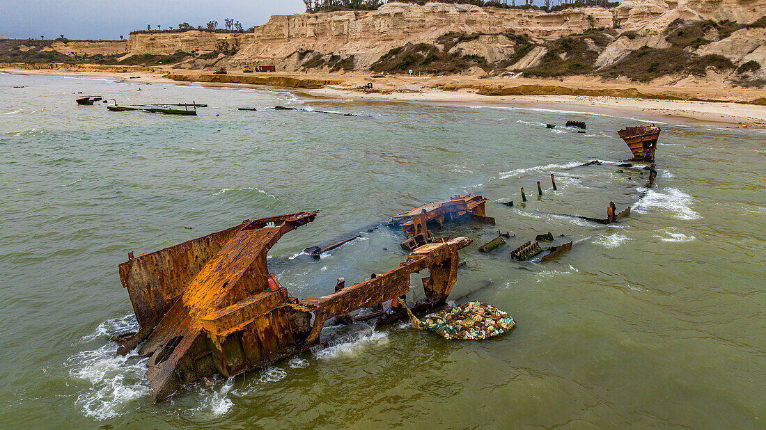 Männer zerlegen ein Boot am Strand des Schiffswracks, Bucht von Santiago, Luanda, Angola, Afrika