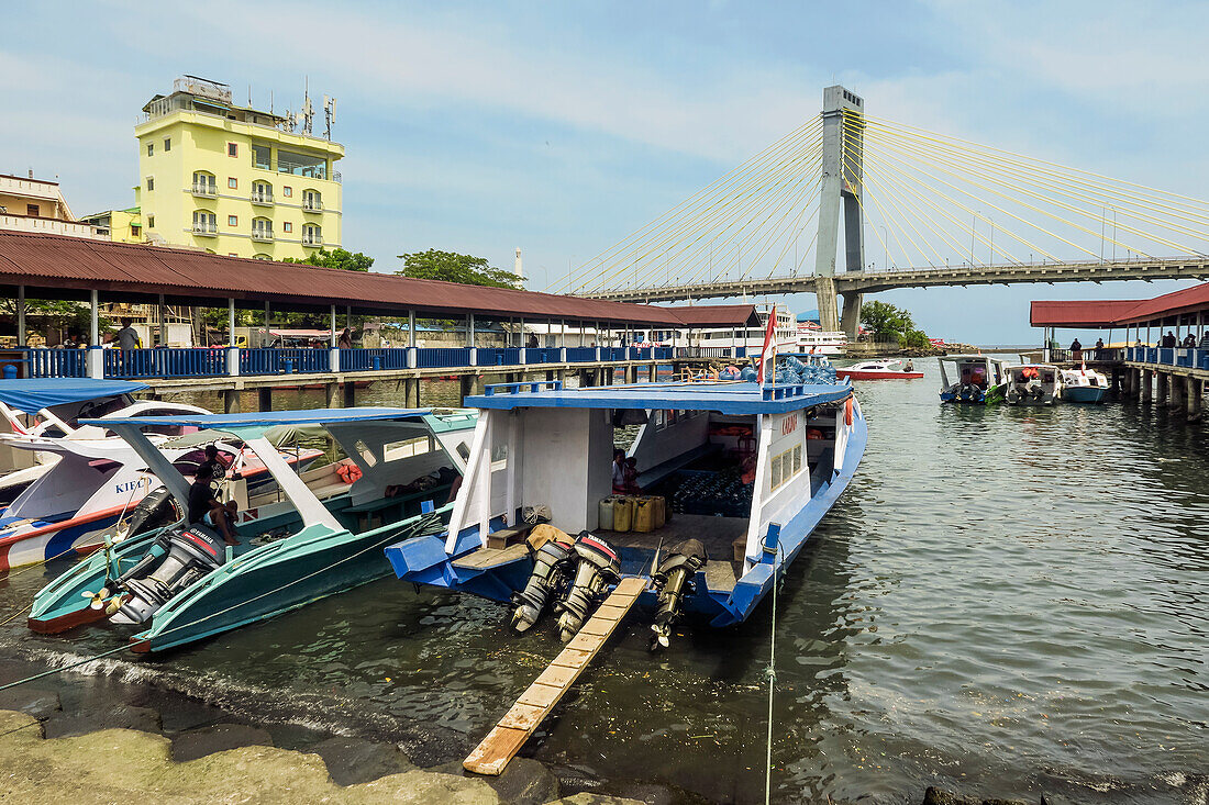 Covered ferry boats in Manado port with Soekarno Bridge beyond in provincial capital of Sulawesi's far north, Manado, North Sulawesi, Indonesia, Southeast Asia, Asia