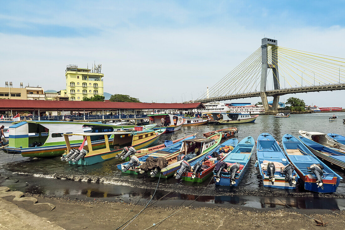 Typische Fährschiffe im Hafen von Manado mit der Soekarno-Brücke dahinter in der Provinzhauptstadt von Sulawesis hohem Norden, Manado, Nordsulawesi, Indonesien, Südostasien, Asien