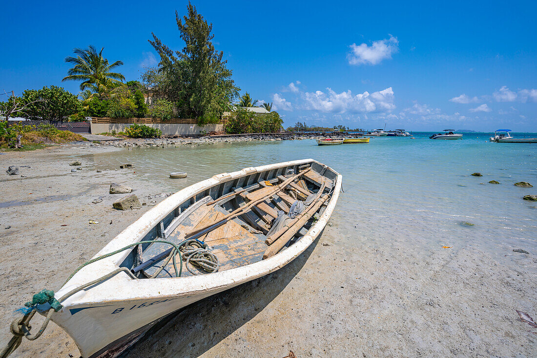 Blick auf ein Boot am Strand und den türkisfarbenen Indischen Ozean an einem sonnigen Tag in der Nähe von Poste Lafayette, Mauritius, Indischer Ozean, Afrika