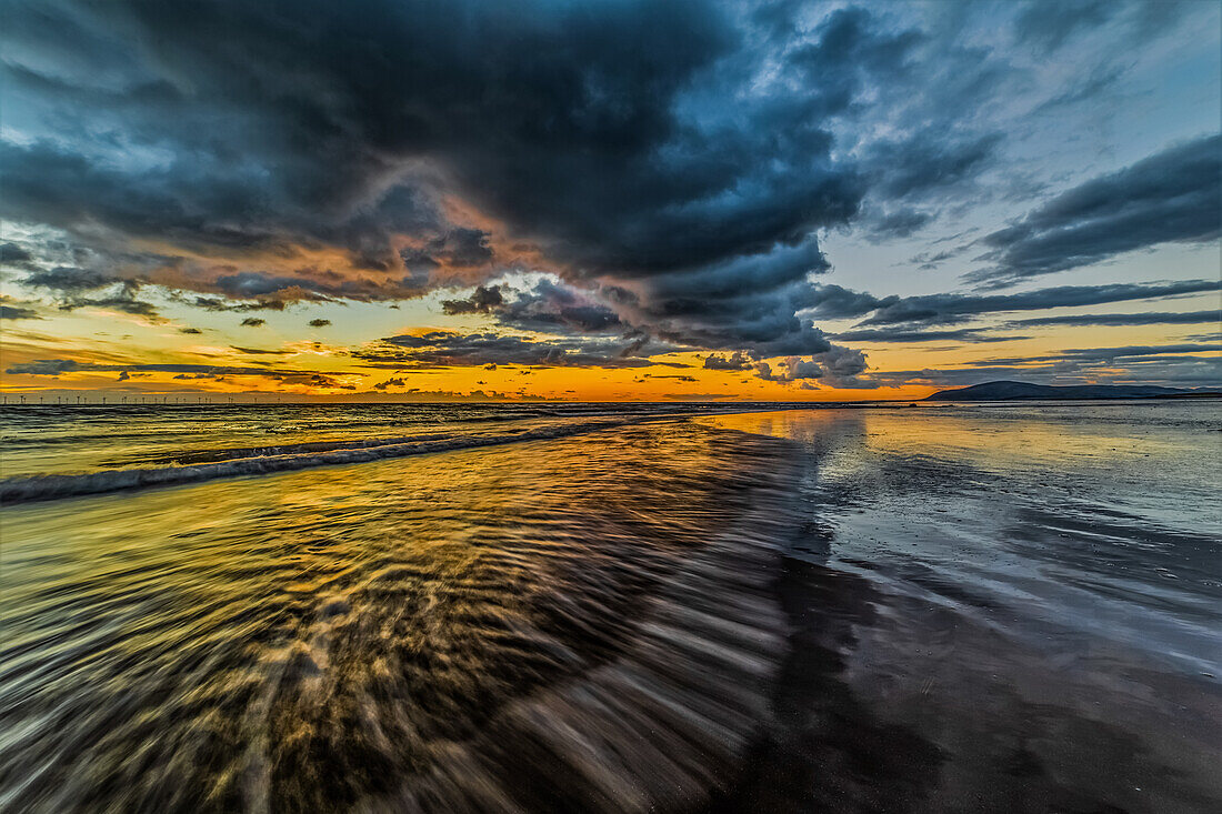 Blick bei Sonnenuntergang von der Insel Walney über die Irische See auf den entfernten Offshore-Windpark Walney, Küste von Cumbria, Cumbria, England, Vereinigtes Königreich, Europa