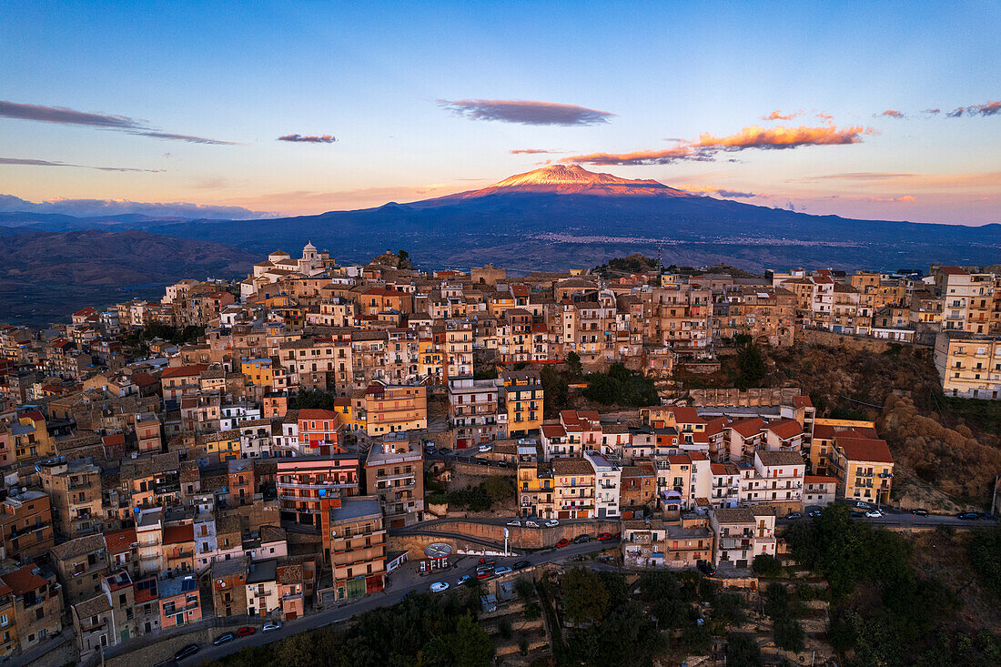 Aerial view of the old village of Centuripe with Mount Etna volcano covered with snow and lit by the sunset, Centuripe, Enna province, Sicily, Italy, Mediterranean, Europe