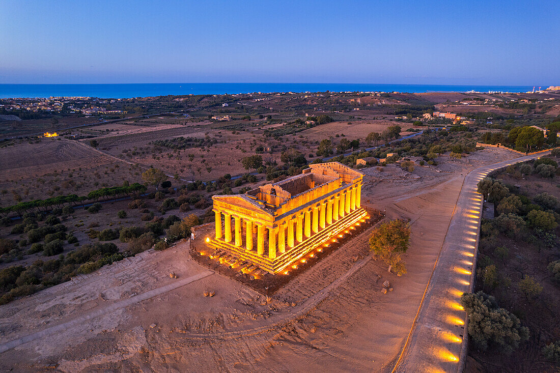 Der beleuchtete Concordia-Tempel von einer Drohne aus gesehen in der Morgendämmerung, Tal der Tempel, UNESCO-Weltkulturerbe, Agrigento, Sizilien, Italien, Mittelmeer, Europa