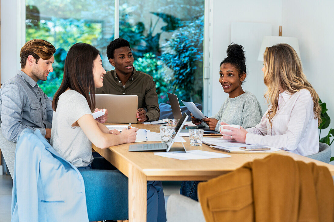 Business people discussing project while gathered at office