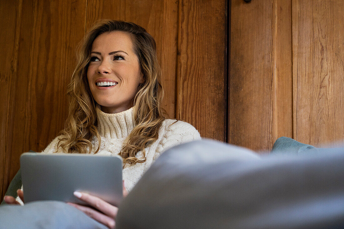 Niedriger Blickwinkel einer erwachsenen Frau, die im Bett sitzend ein digitales Tablet benutzt