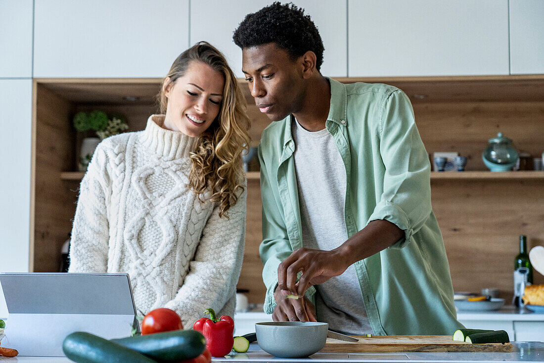 Couple looking at cooking recipe on digital tablet while standing at kitchen counter