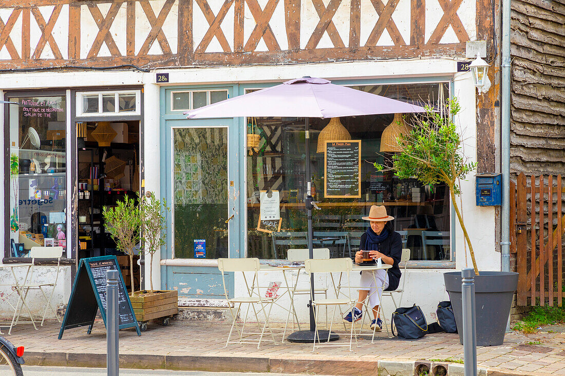 Tourist sitzt im Cafe im Normandie-Dorf Beuvron-en-Auge, Beuvron-en-Auge, Normandie, Frankreich, Europa