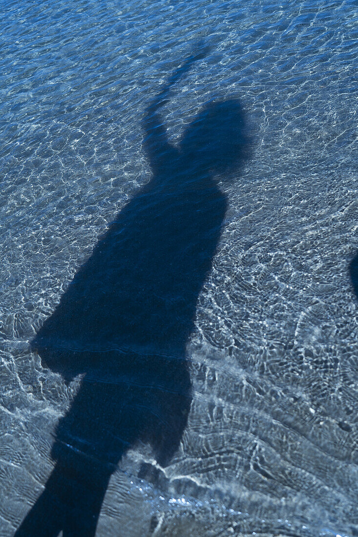 Shadow of unidentified person on blue water