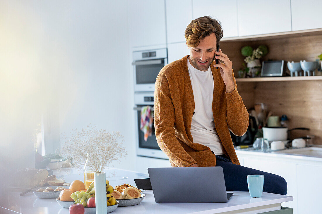 Adult man having a phone call while using laptop
