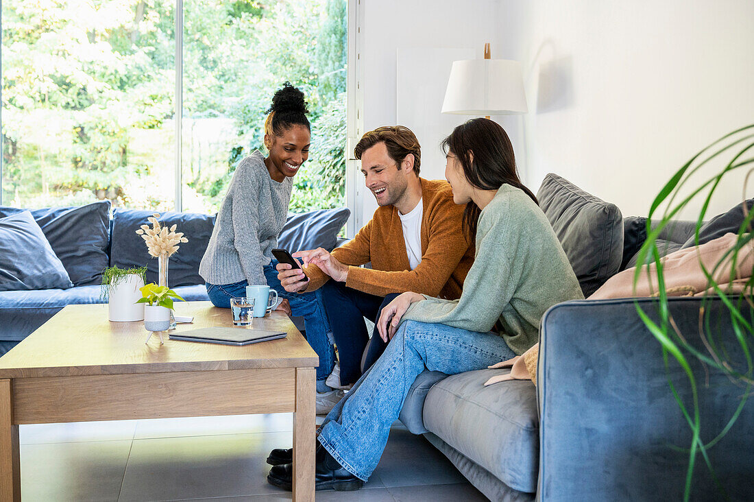 Small group of friends gathered in living room while using smart phone