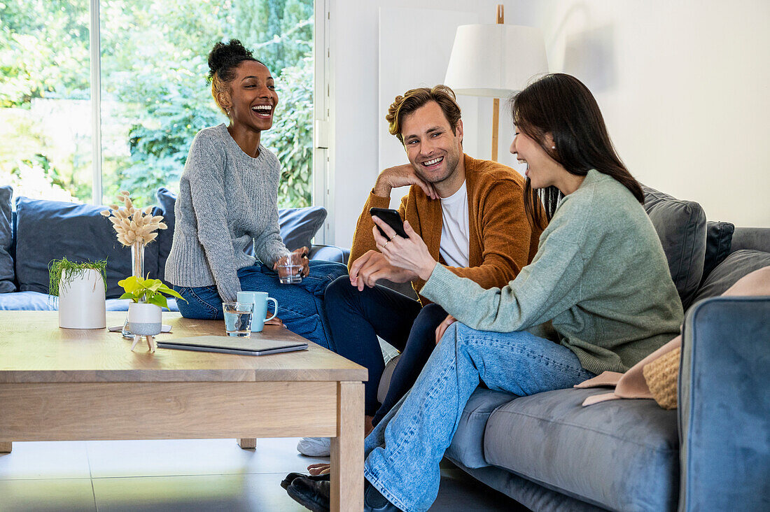 Small group of friends having fun while hanging on living room