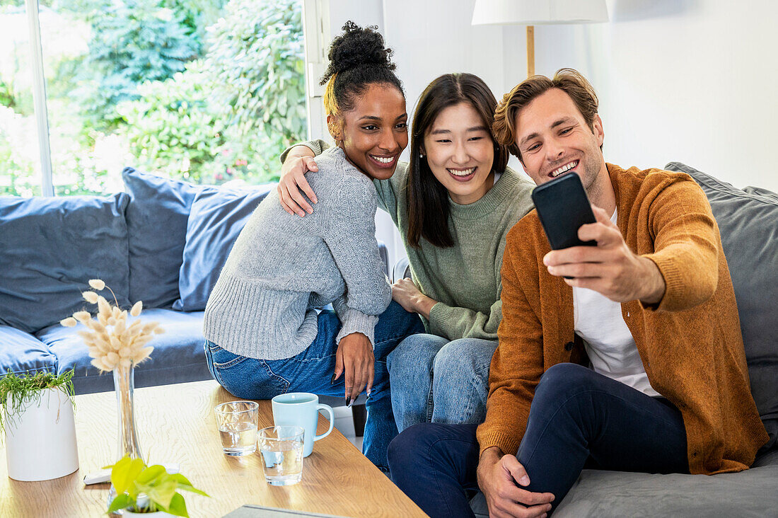 Small group of friends taking a selfie while sitting on sofa