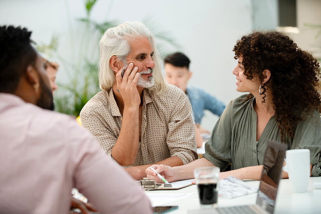 Adult businessman listening to female coworker during meeting