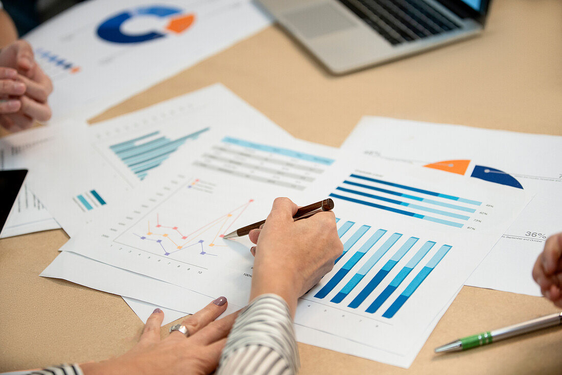 High angle view cropped image of business people working with printed charts