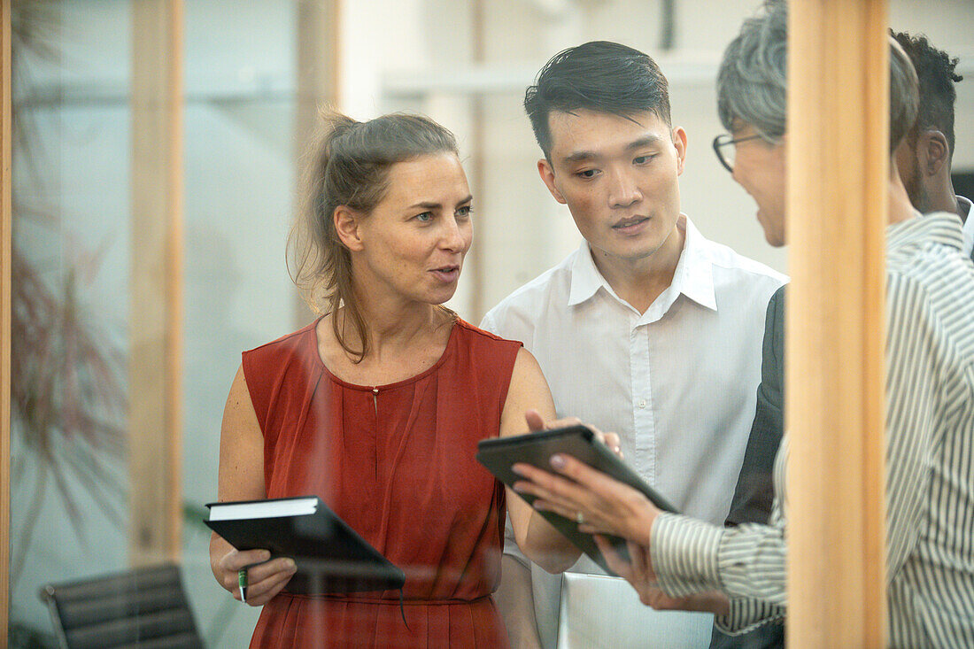 Businesswoman discussing over digital tablet with coworkers