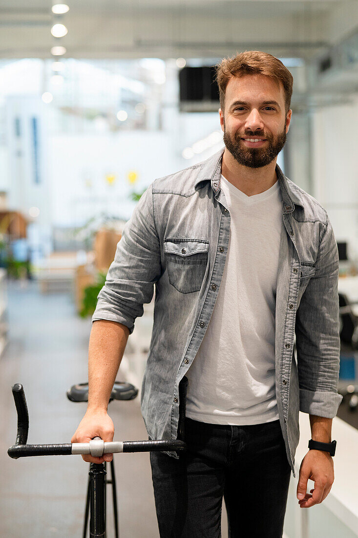 Männlicher Unternehmer verlässt sein Büro, während er mit dem Fahrrad an seiner Seite spazieren geht