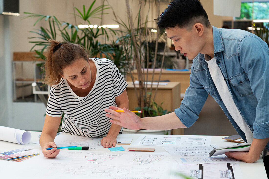 Architects discussing over blueprint while leaning on table