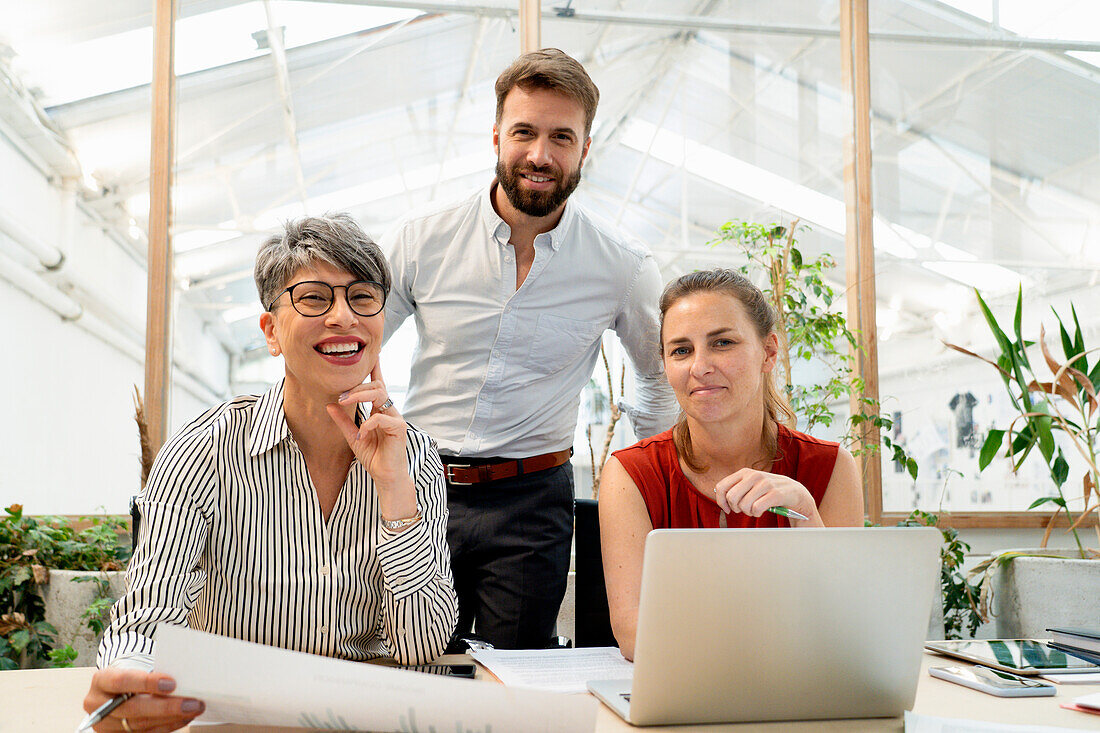 Group of coworkers looking and smiling at the camera while working at office