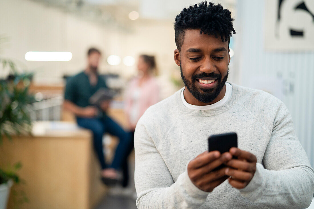 Afroamerikanischer Mann schreibt eine SMS auf einem Smartphone