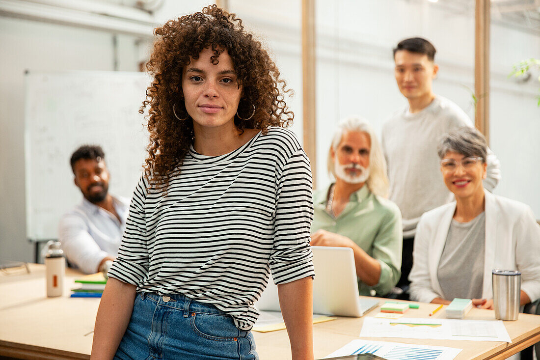 Project manager standing while looking at the camera during meeting