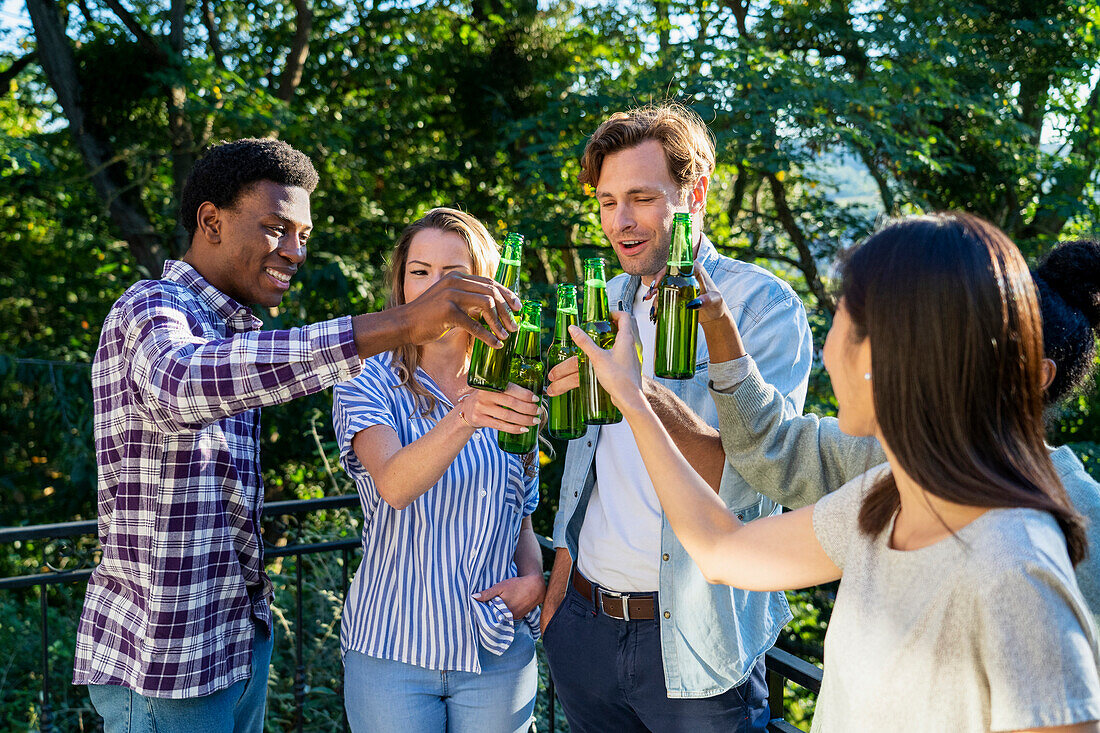 Group of friends toasting with beer bottles standing outdoors