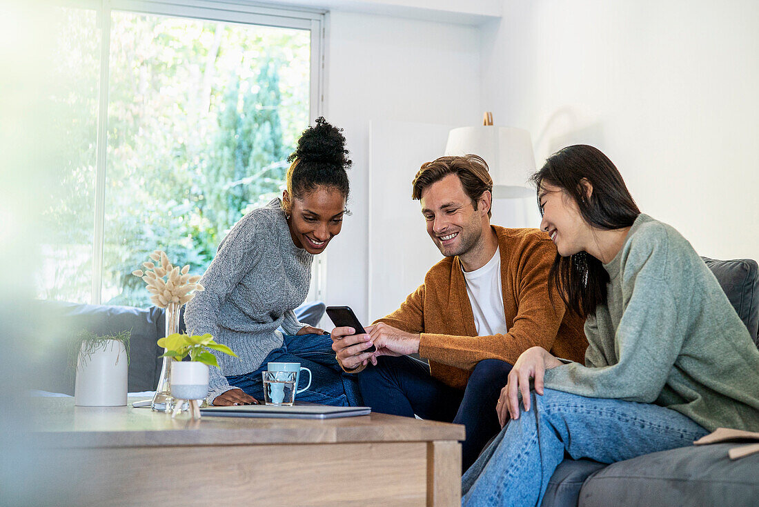 Small group of friends gathered in living room while using smart phone