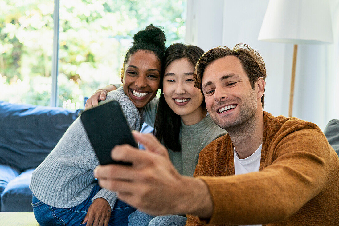 Small group of friends taking a selfie while sitting on sofa