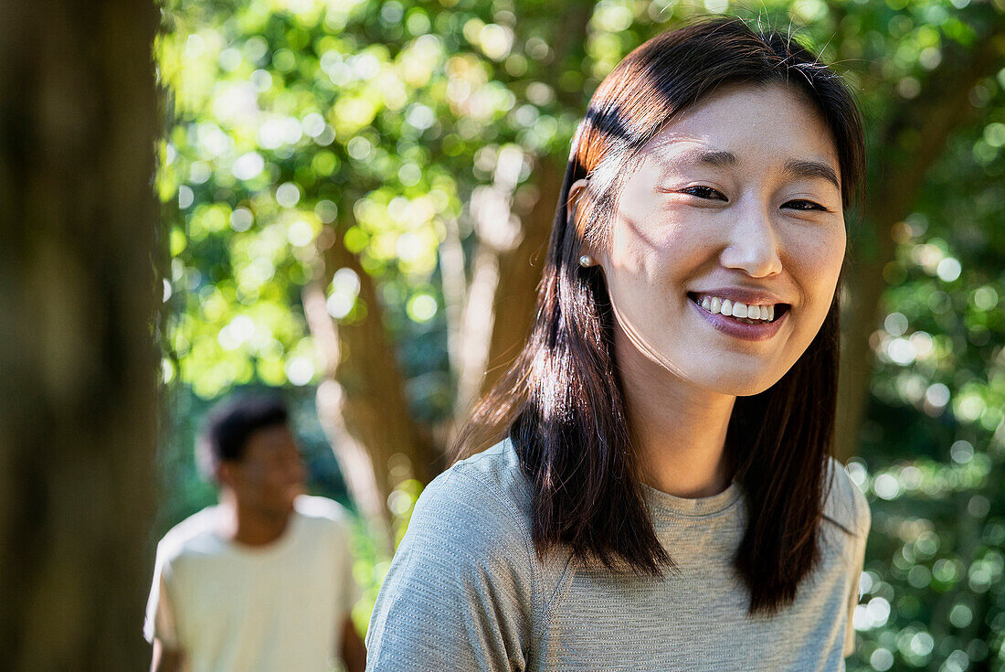 Adult woman hiking with boyfriend in the woods looking at the camera