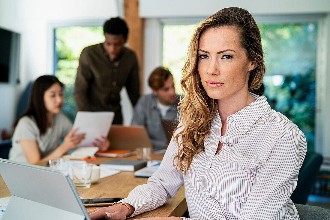 Financial worker looking at the camera while using digital tablet