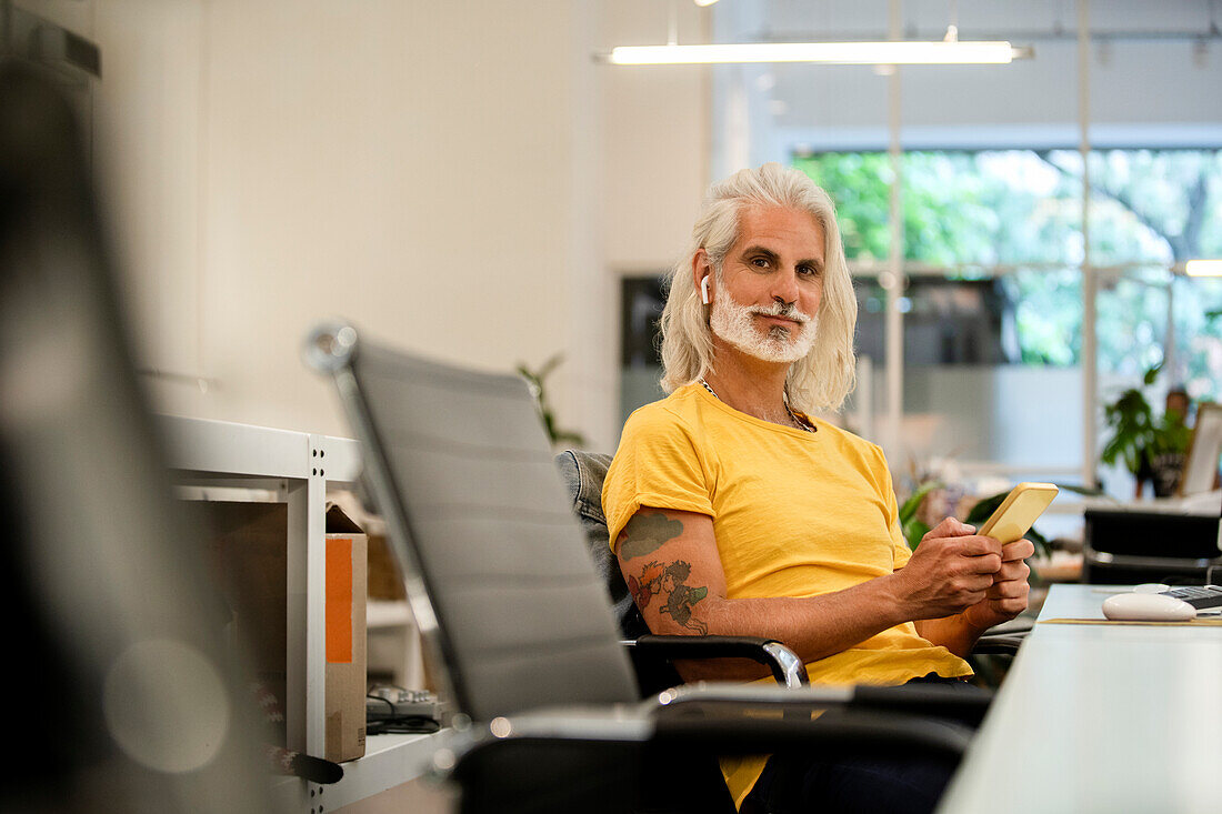 Male computer programmer looking at the camera while using smart phone