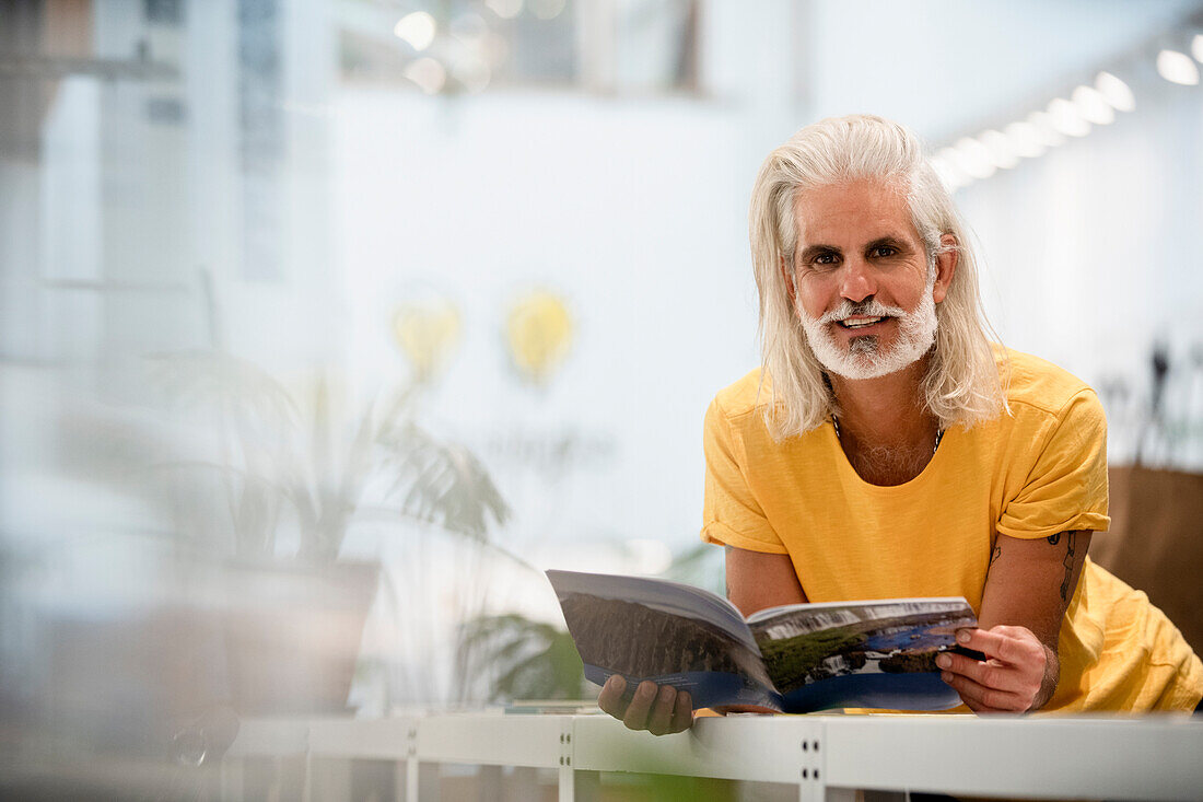 Adult male designer leaning on table while looking at the camera