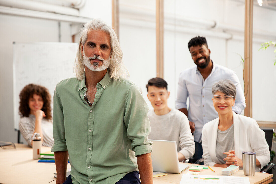 Männlicher Industriedesigner, der in die Kamera schaut, während er in einem Büro steht