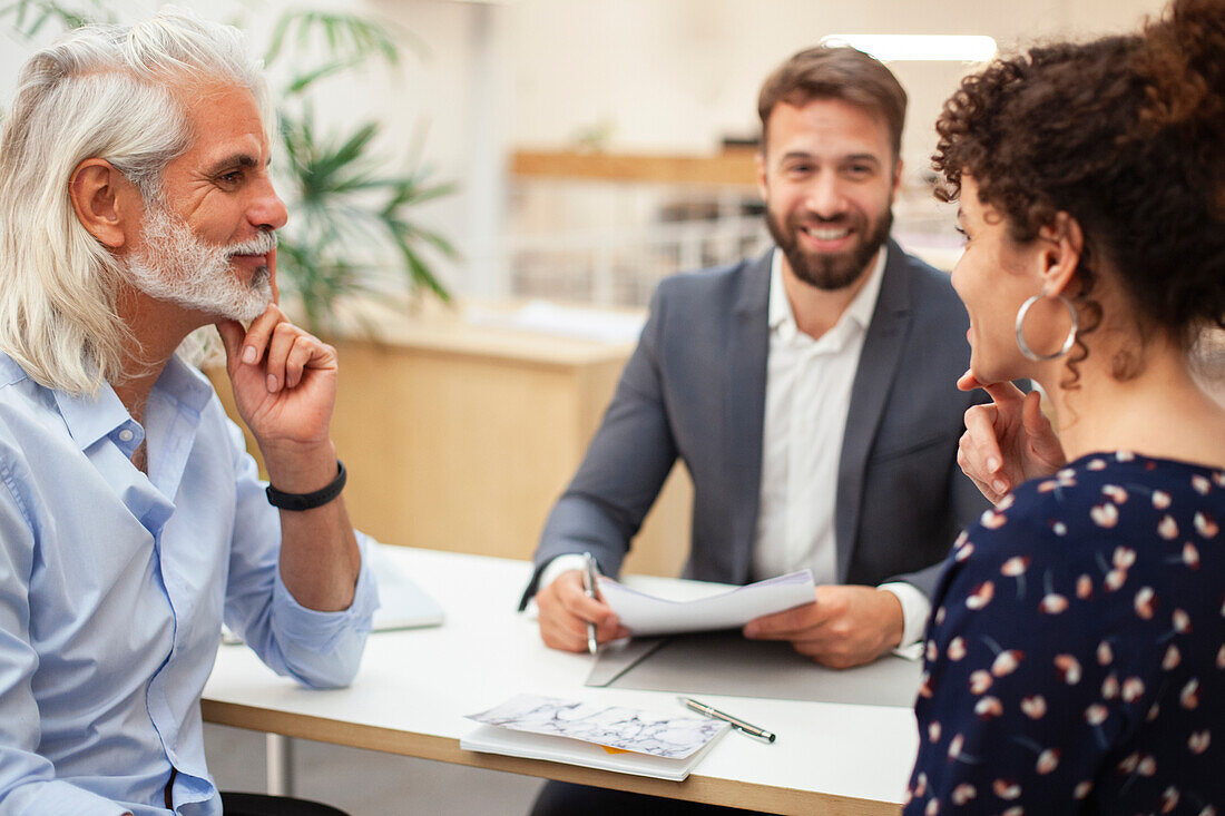 Thoughtful adult couple looking face to face during meeting with real estate agent