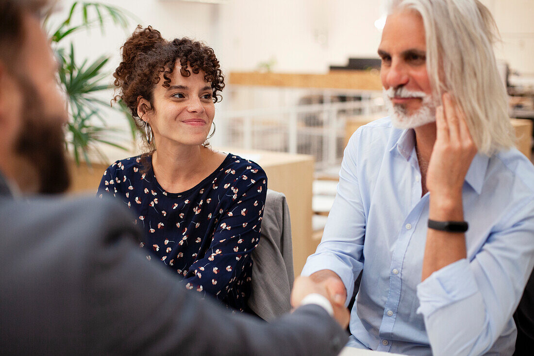 Adult woman looking at husband while he is shaking hands with lawyer