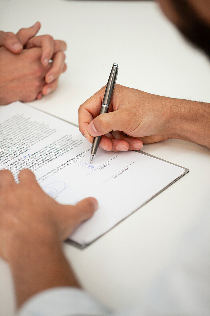 Nahaufnahme einer Unbekannten, die einen Vertrag mit einem Stift unterschreibt