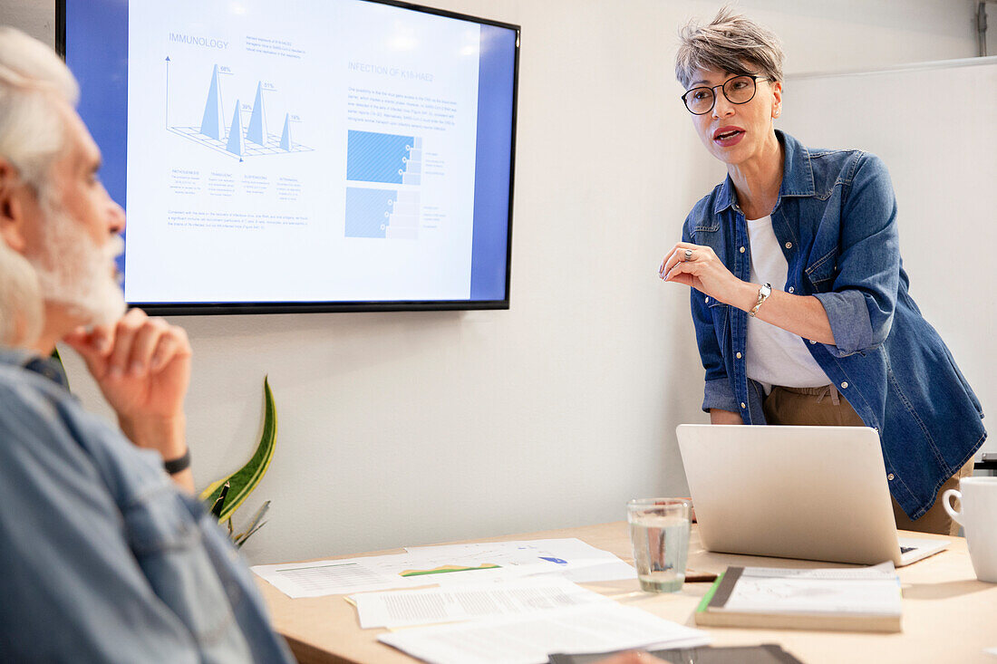 Project manager discussing with male coworker during presentation