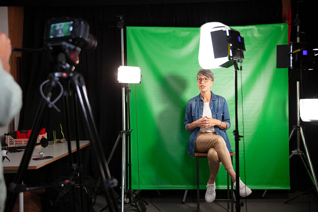 Mid adult woman giving an interview while sitting against green screen